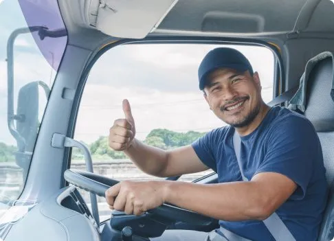 Guy driving a truck smiling with his thumbs up